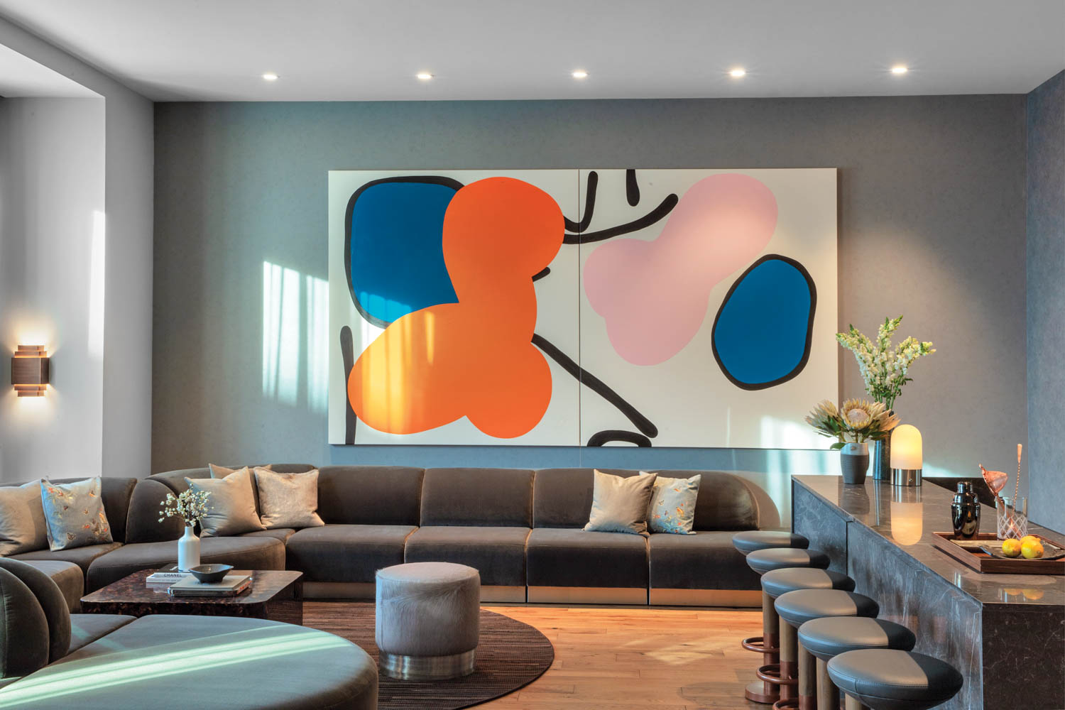 Back­dropped by a Danni Pantel acrylic on canvas, the penthouse suite’s custom sectional is also mohair-covered. Photography by Eric Laignel.