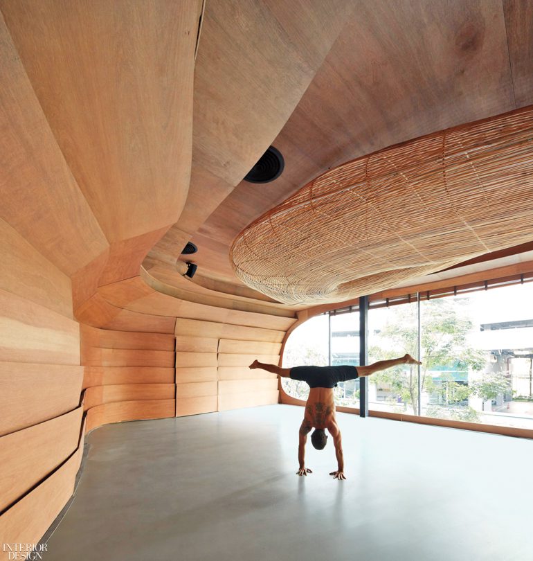 A yoga studio with curved rattan roof and a person in an handstand