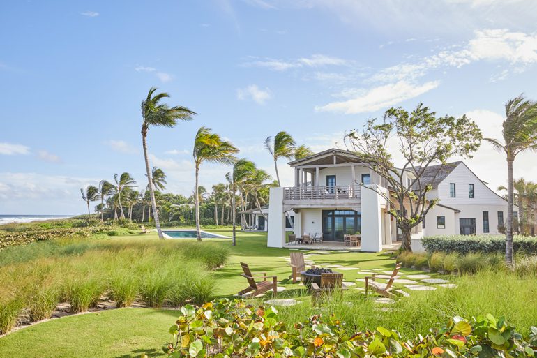 The facade of a florida home with sweeping beach grass and a pool