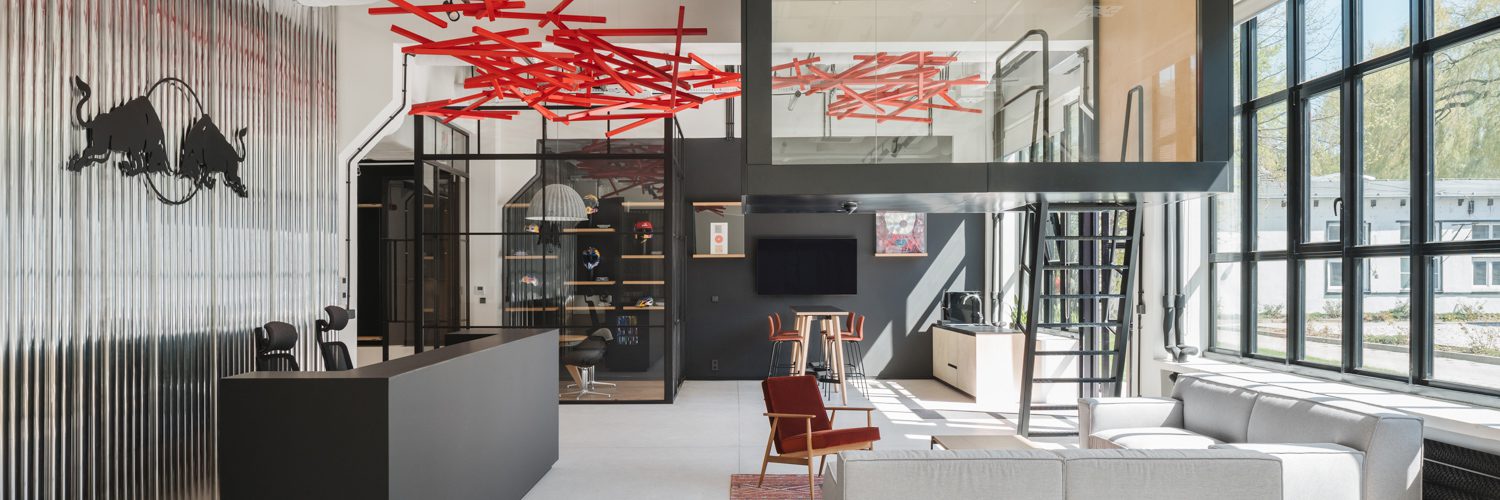 An installation called Wave of Energy swoops above the entrance area in Red Bull’s Warsaw offices, designed by MXCF Architekci.