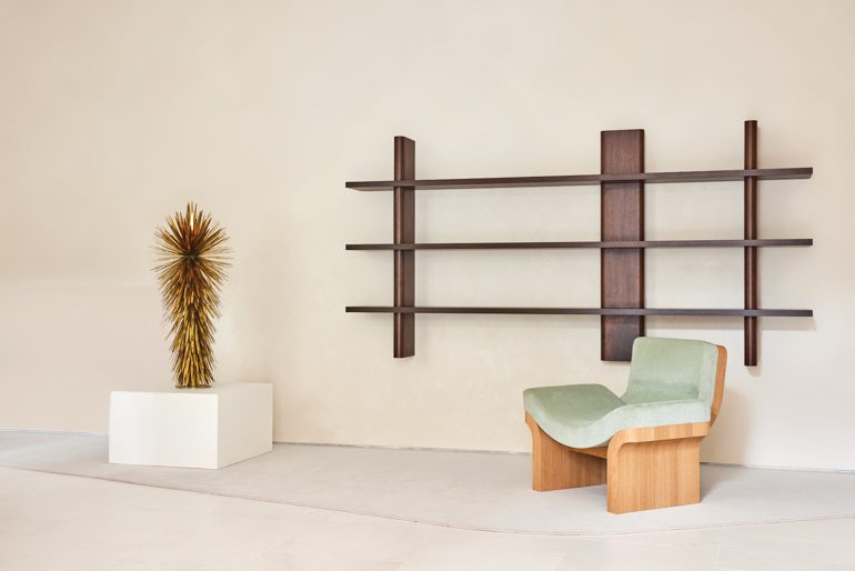 a bronze sculpture and an oak chair flanking Egg Collective’s wall-mounted Landry bookcase