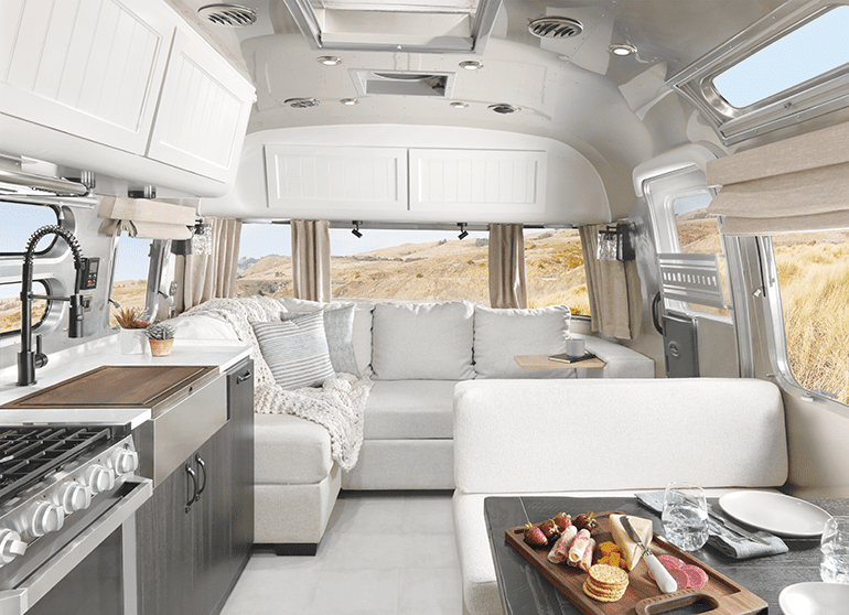 The interior of an airstream travel trailer with white sofa and bench