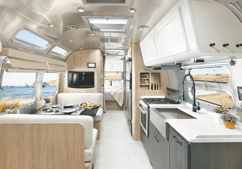 The airstream travel trailer features a sink and stove with a dining area