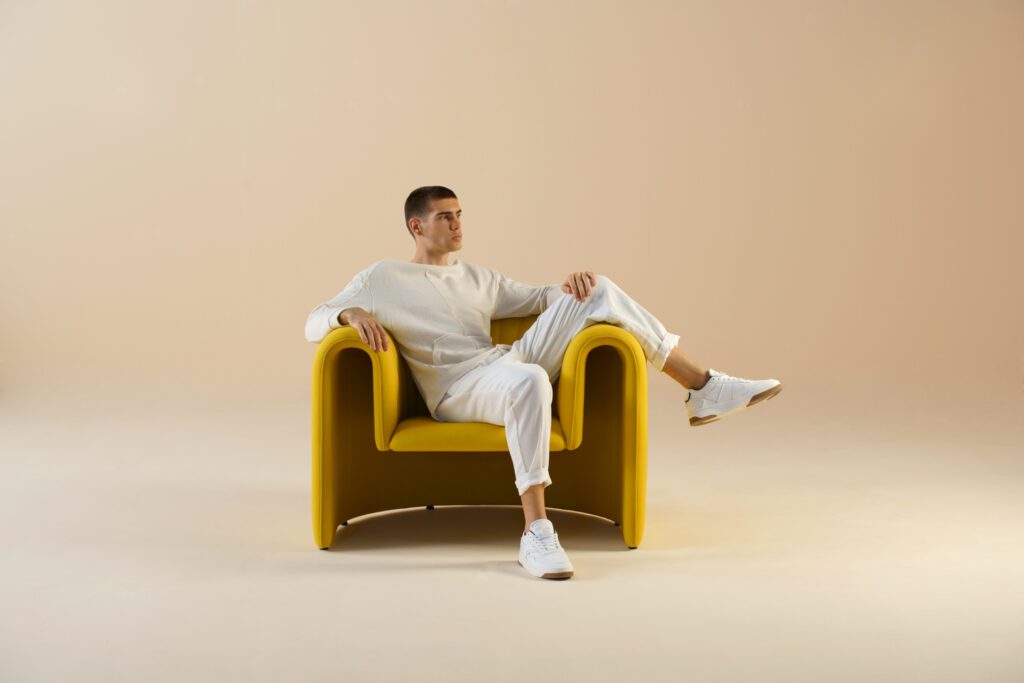 Person sitting in a golden u-shaped armchair.