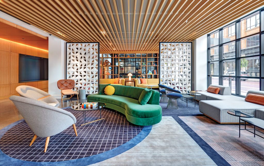 A bright green curved sofa adds a pop of color beneath a ceiling made from wood slats.