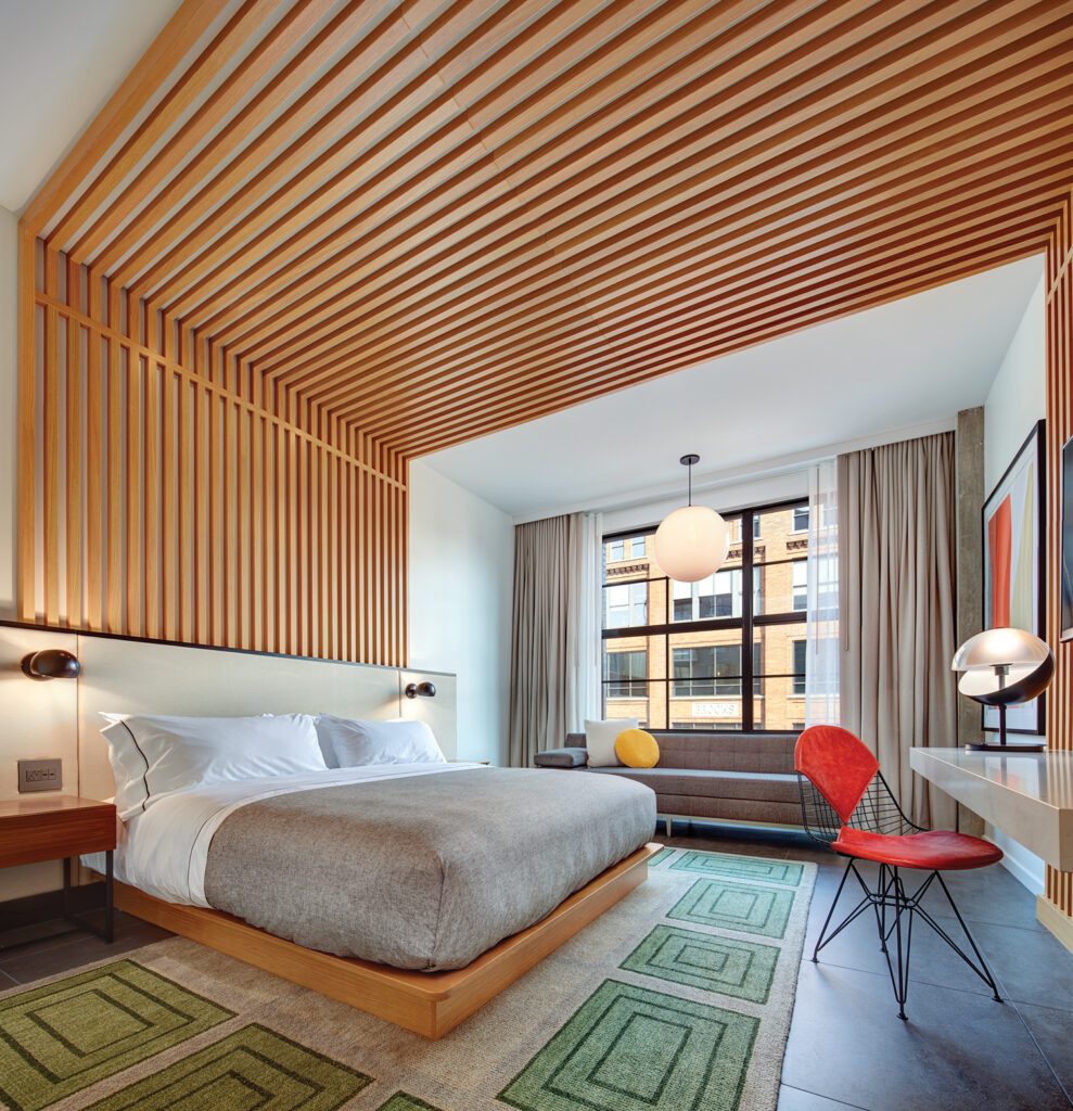 Wood slates line the ceiling and back wall, offering a unique headboard for the bed in this guest room.