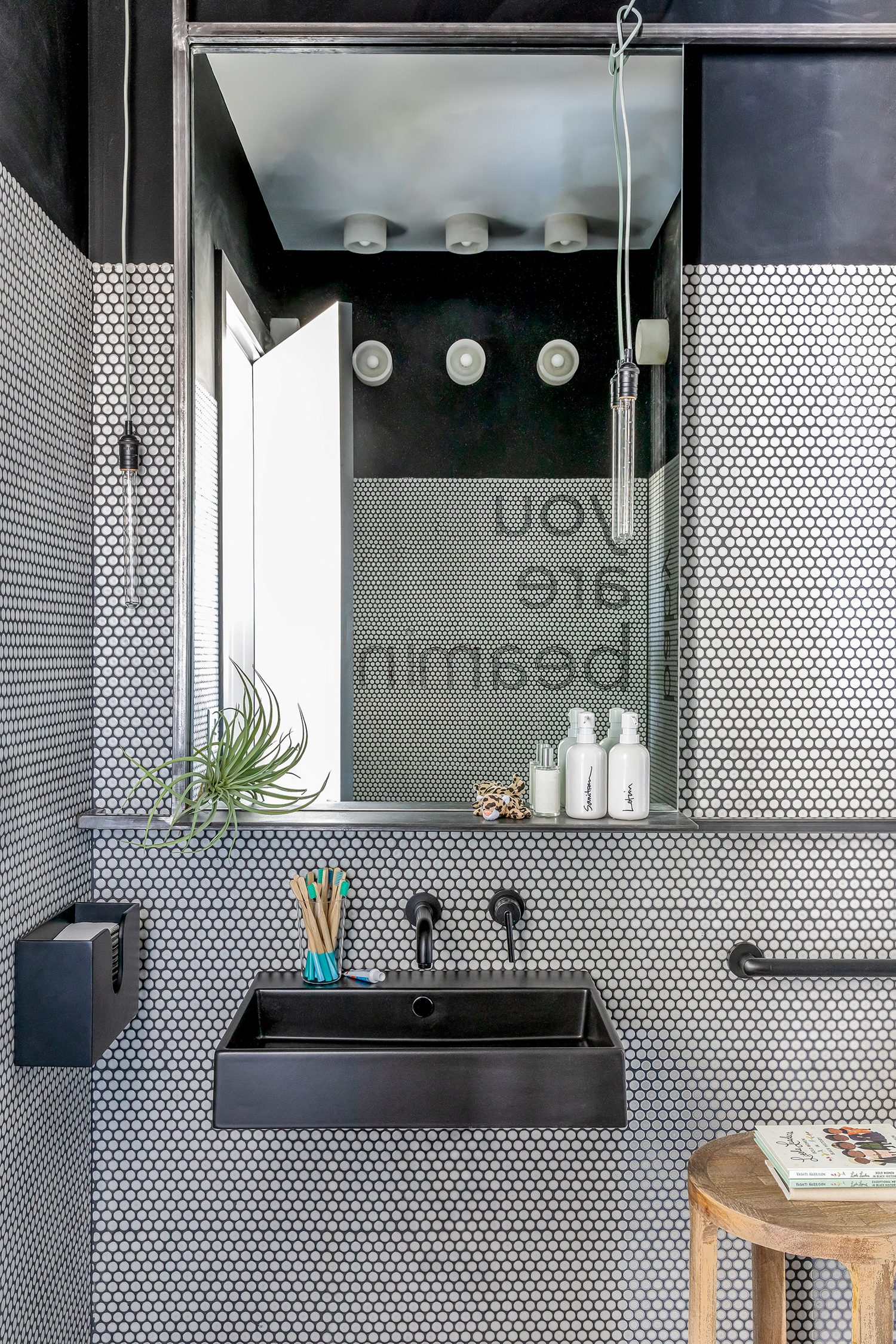 A bathroom, clad in Ann Sacks penny tile, offers wood toothbrushes.