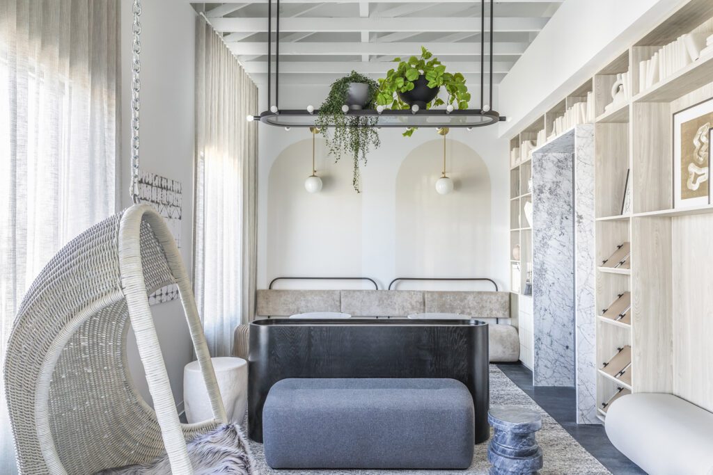 A waiting area for adult patients offers an Arteriors wicker hanging chair, Noir tables, a small bench upholstered in Carnegie fabric, and a longer bench by the wall upholstered in Holly Hunt’s Great Outdoors.