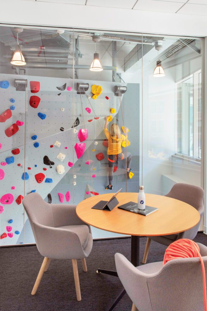 An interview room with a Jephson Robb table and Naoto Fukasawa chairs overlooks the climbing wall.