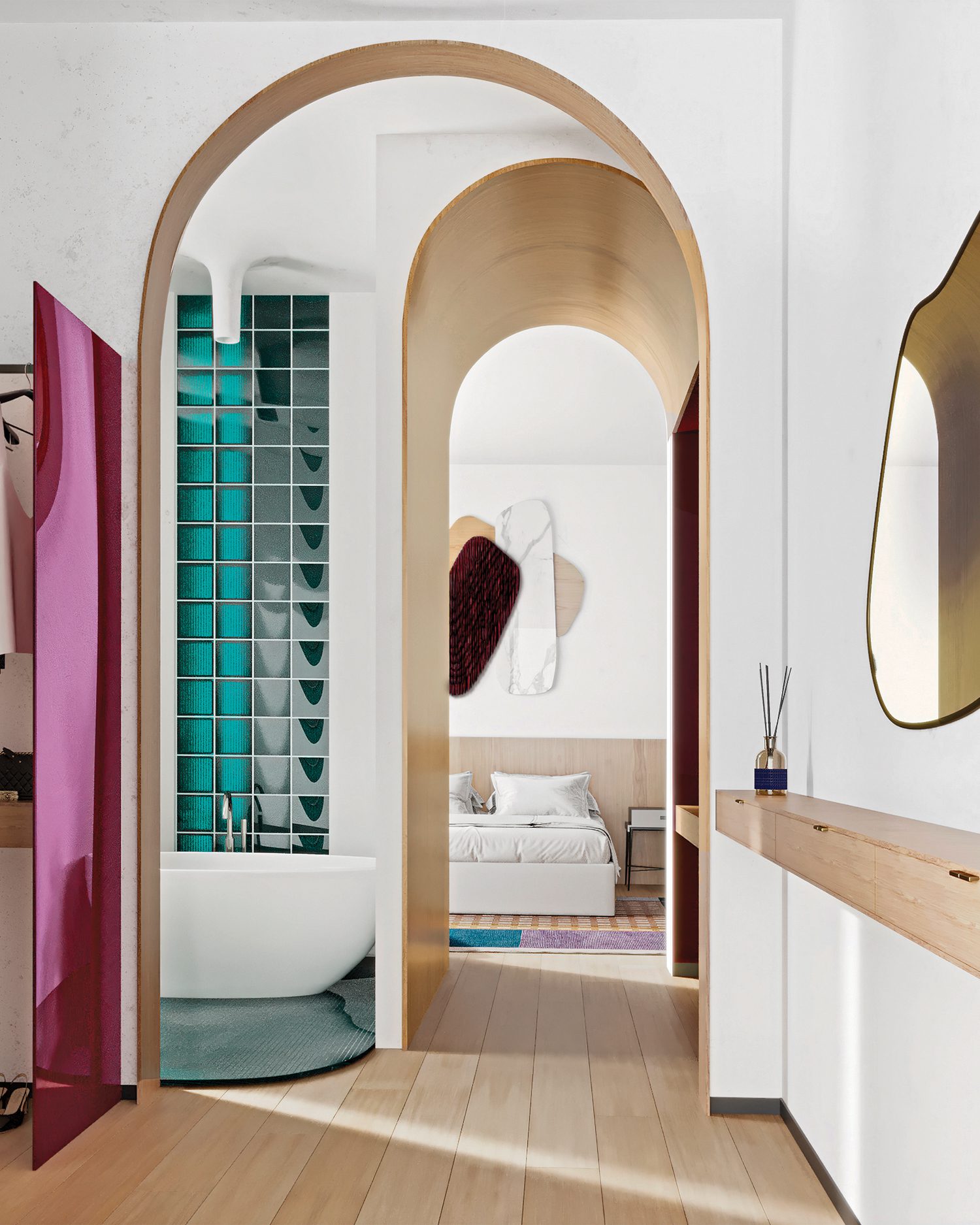 An enfilade of archways connects the bedroom to the bathroom and walk-in closet, where an artsy partition is formed from glass panels sandwiching colored film.