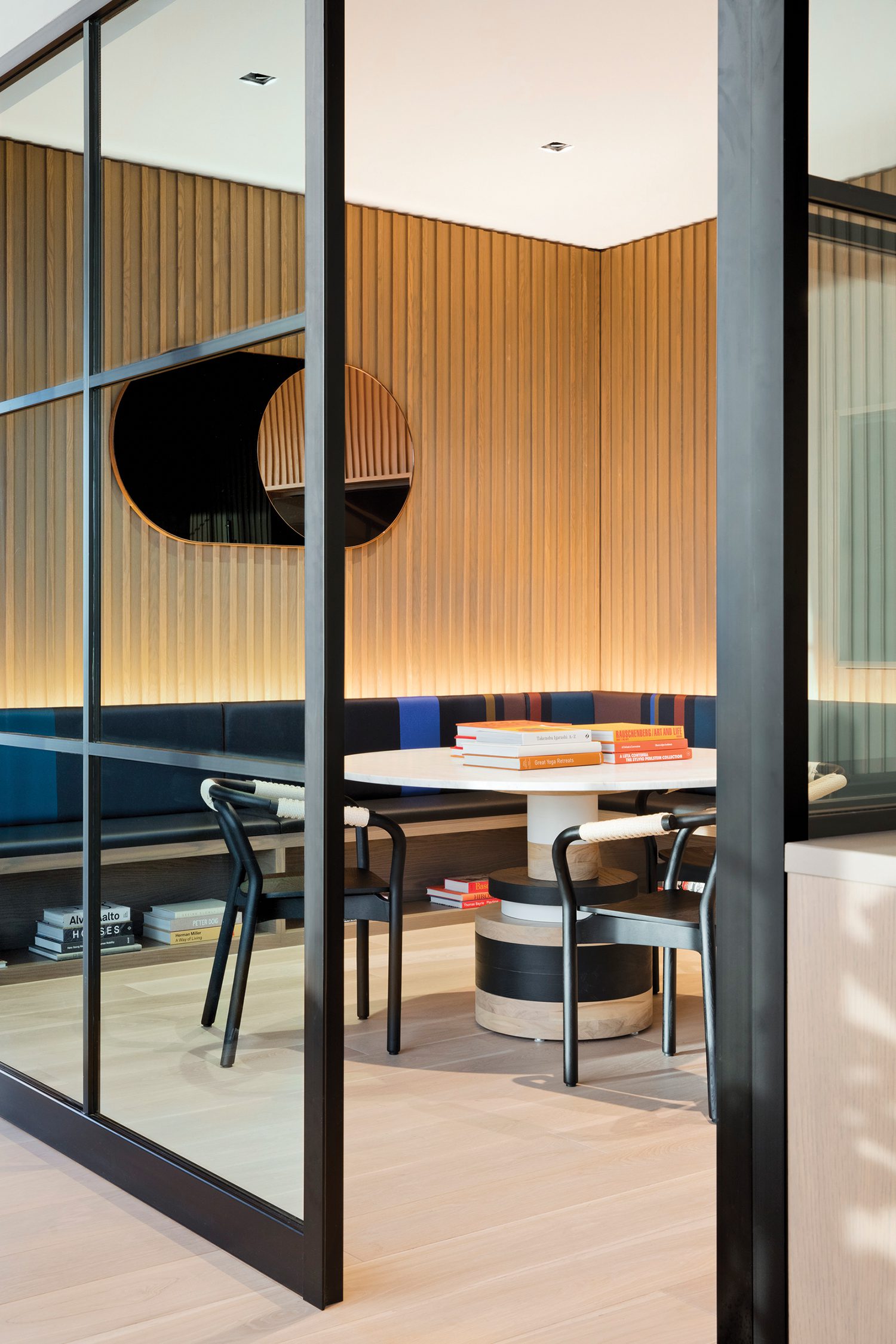 A Bower Studios mirror, Souda’s Sass table, and Paul Smith’s Big Stripe upholstery on the built-in bench furnish a meeting room.