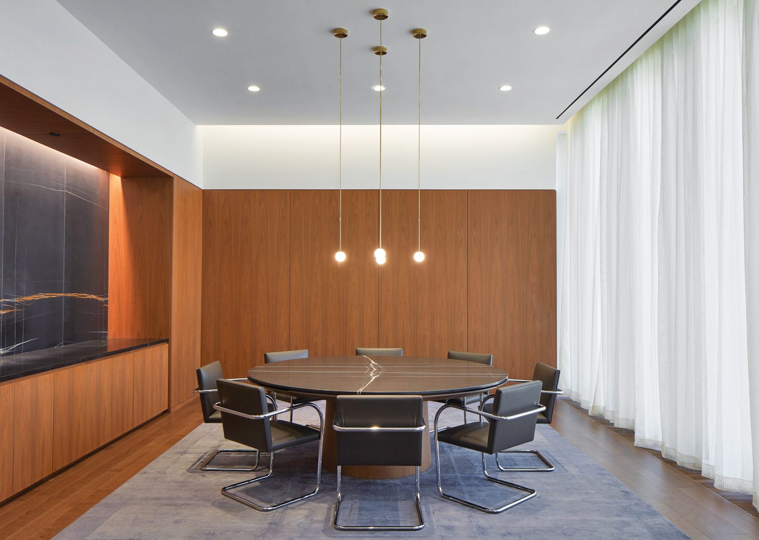 Sahara Noir marble forms the feature wall and custom table’s top in an executive meeting room with white oak flooring.