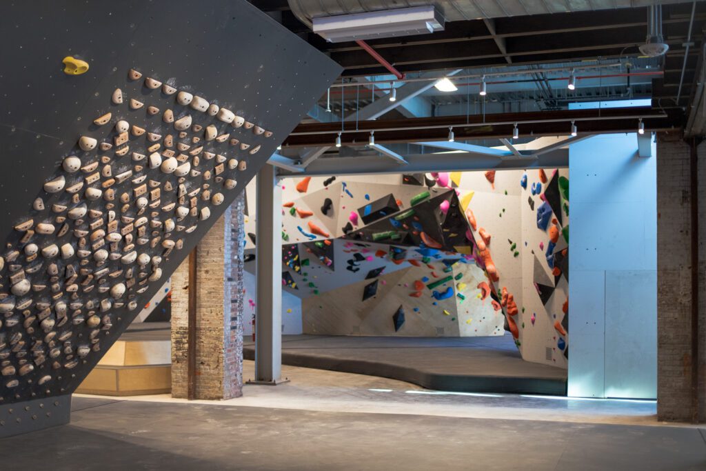 Exposed brick columns remain from the building’s original construction, next to brand-new plywood and steel climbing walls by Vertical Solutions.