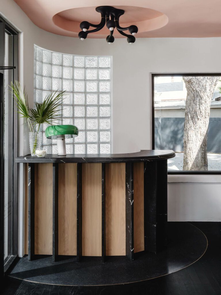 The hostess stand is topped with a chandelier by Entler and includes cabinetry by Madera Millwork.