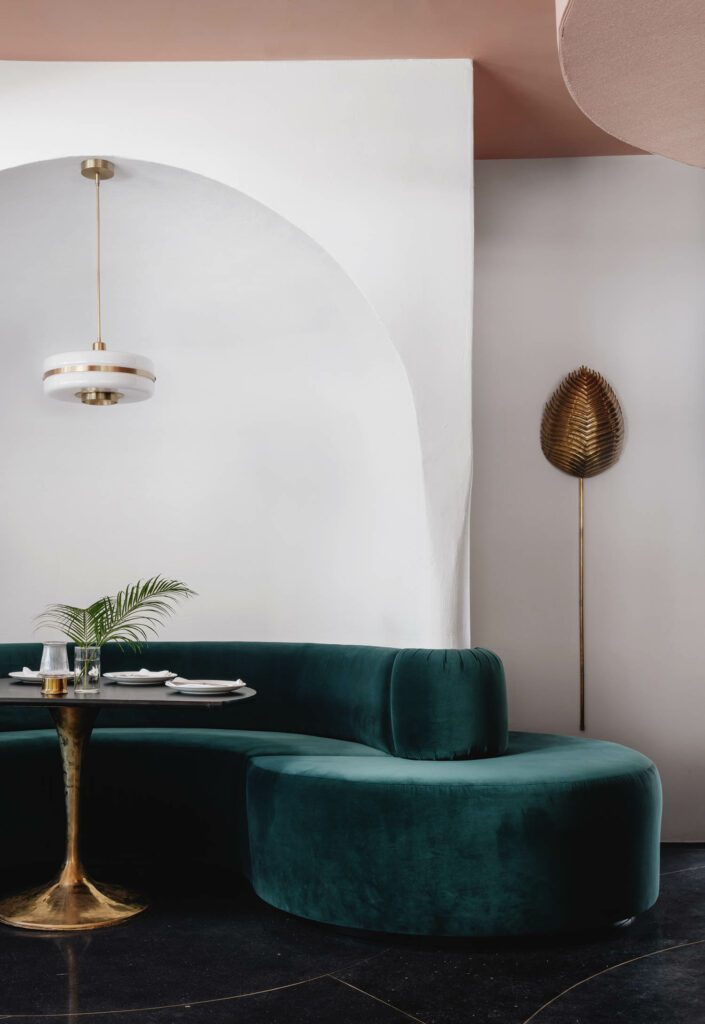 In the main dining room, brass work includes custom pendants by Bert Frank. Under Cover Upholstery crafted the sofas alongside Austin Leaf sconces by Arteriors Home.