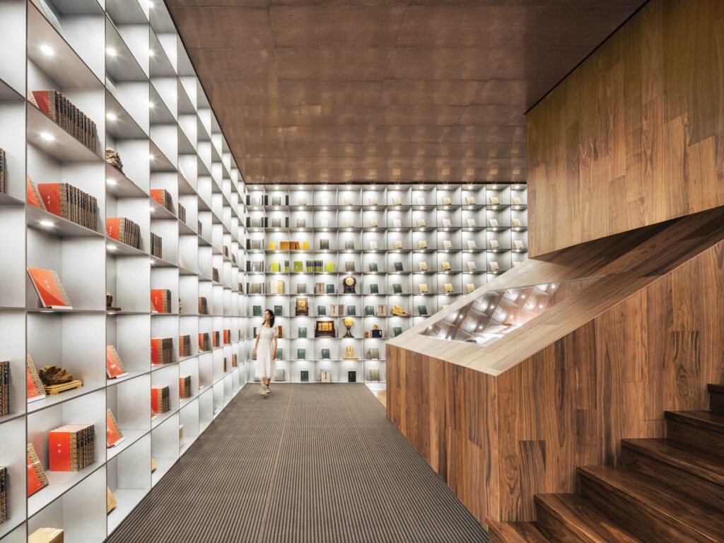 Steel shelves sur­round­ed by walnut composite contain the rare books collection.