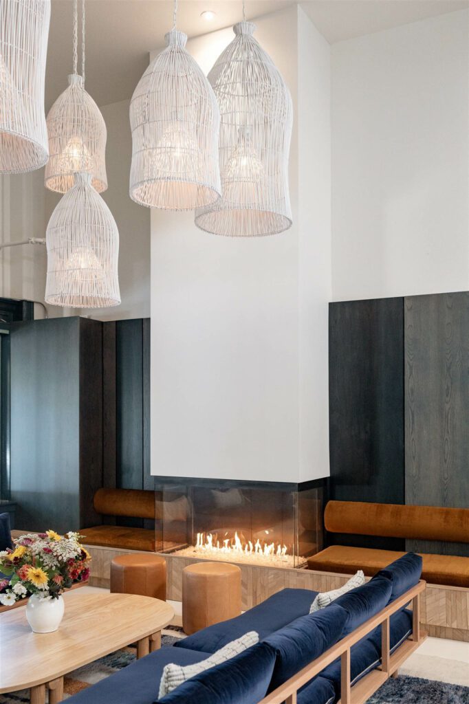 A three-sided bay glass fireplace with heat-tempered glass is flanked by two built-in benches covered in Foret custom paneling from France.