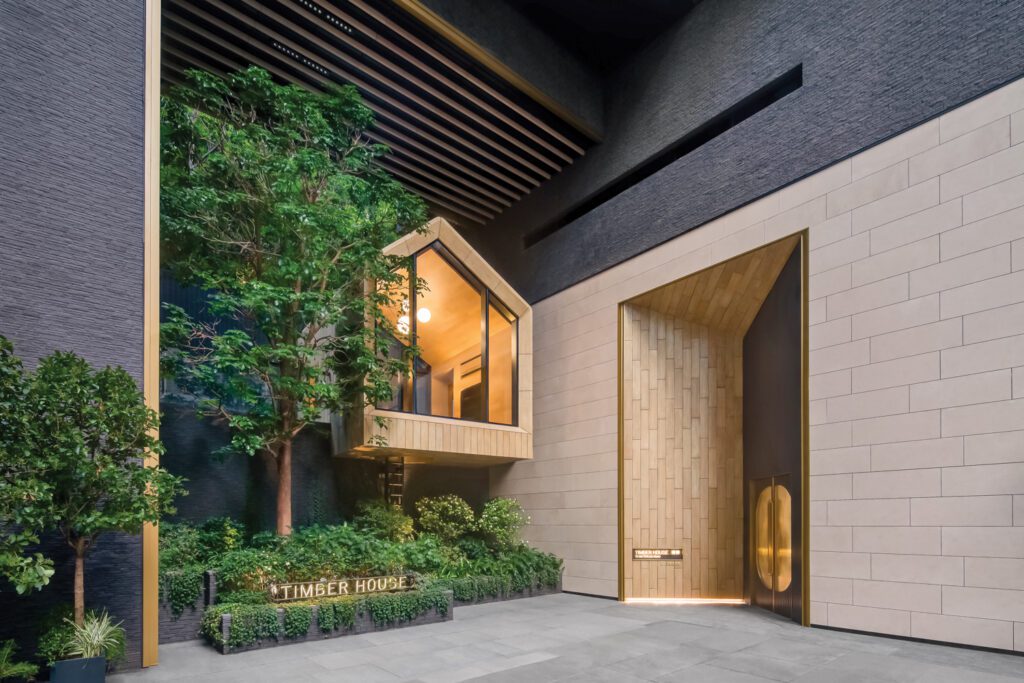 Floating amid tropical foliage, a wood cabin marks the entry to Timber House, a Hong Kong residential tower with interiors by NC Design & Architecture.