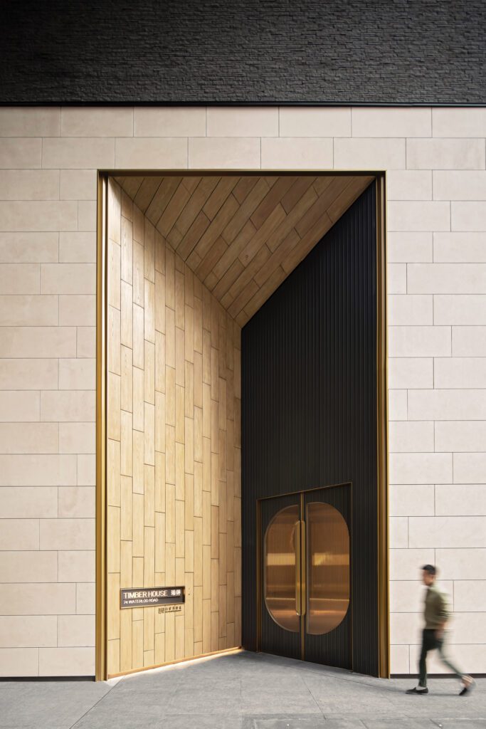 Powder-coated corrugated steel clads the entry doors and surrounding wall, while fluted glass insets allow daylight into the lobby.