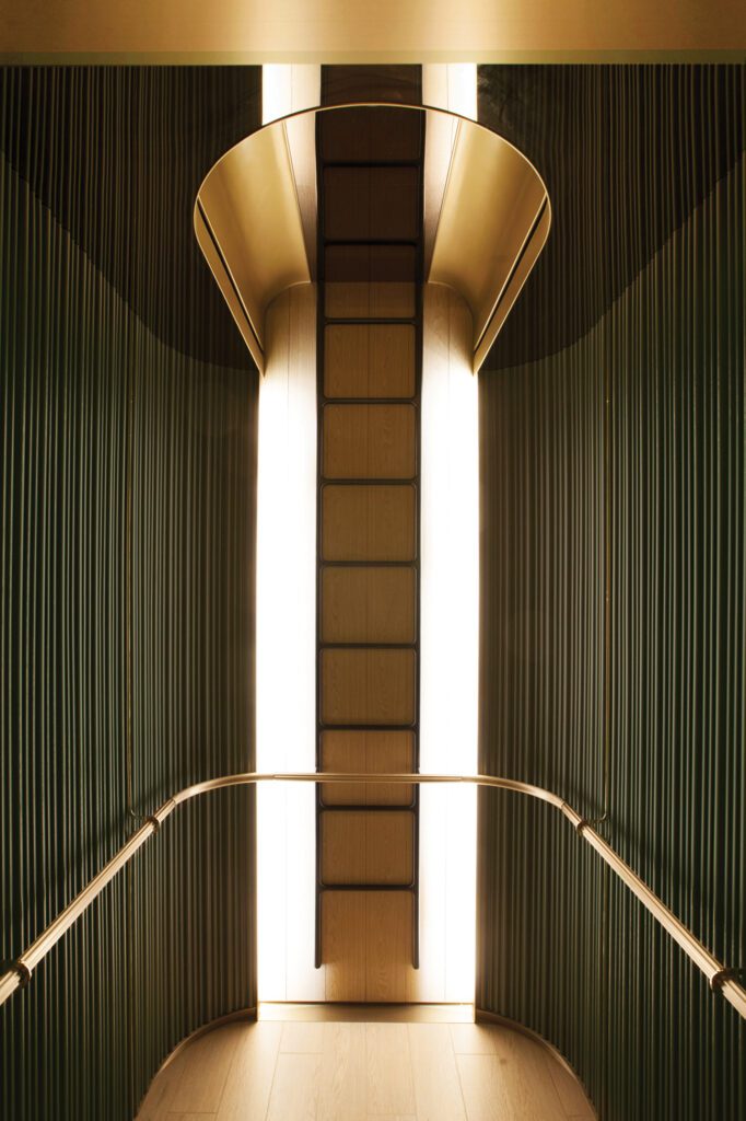 Reflected in an elevator cab’s mirror ceiling, a custom blackened-steel ladder seems to stretch to infinity.