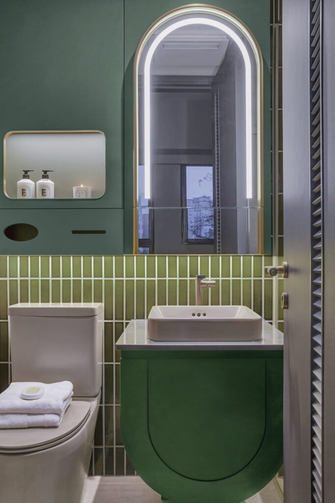 In an apartment bathroom, the curves of the mirror cabinet and sink vanity—both custom—echo one another.