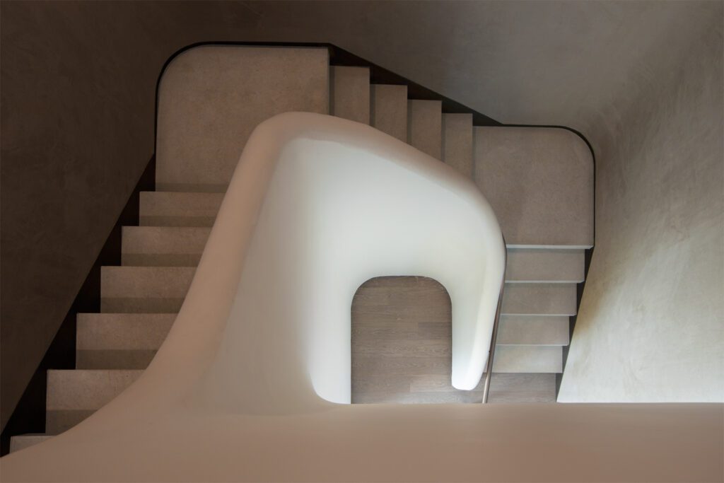 The stairwell serves as a statement in the space given its soft edges and earthy palette.