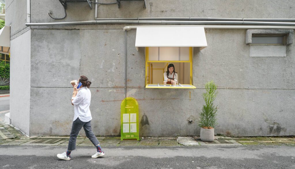 Next to the takeaway window, a translucent yellow sandwich-board serves as a menu.