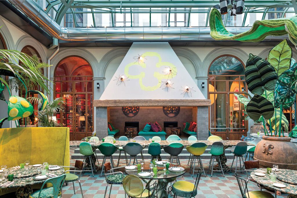 Below the San Paolino restaurant’s glass cupola, chairs made from recycled plastic and metal line a custom marble-top table.