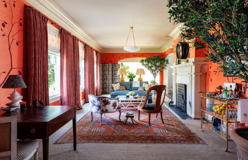 A sitting room with orange wallpaper with thinly drawn trees