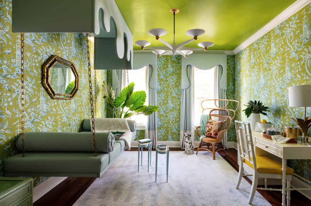 A guest room with walls of green, a green daybed, and rattan and bamboo accessories