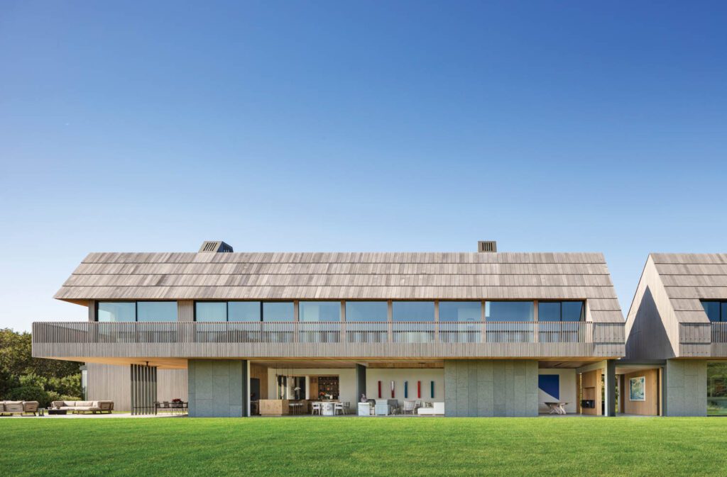 The saltbox form allows for openness and extensive glazing on the ocean-facing side of the house; two bronze-clad “light chimneys” peek over the roofline.