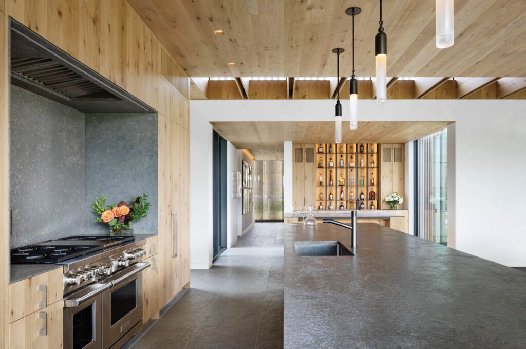 A system of ceiling coffers brings natural light from the rear of the house into the main kitchen, which also boasts Gabriel Hendifar blackened-brass pendant fixtures.