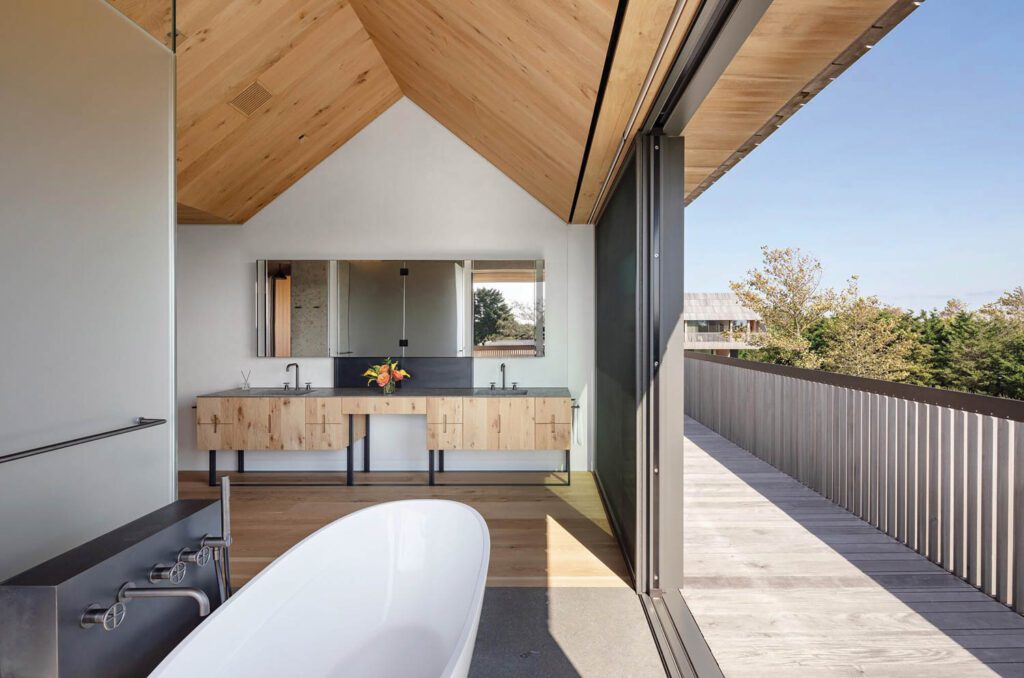 Oak planks clad the floor and ceiling of the main bathroom, which has a custom vanity and freestanding tub.