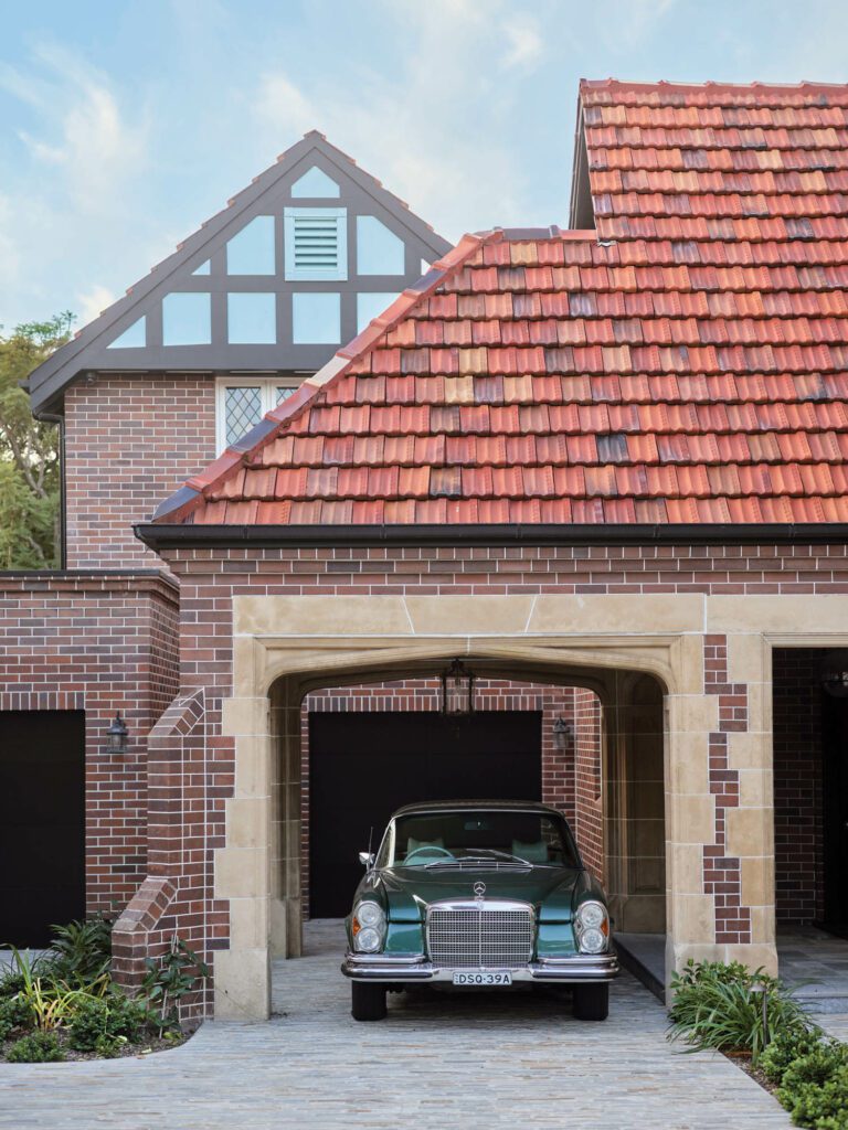 The rear addition housing the game room is visible beyond the Tudor-style main house and accessed via the enlarged six-car garage.