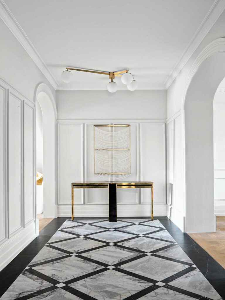 Custom marble parquetry flooring bedecks the foyer, where a Graziela Guardino linen on canvas drapes over a 1970 console by Giacomo Sinopoli; the pendant is an Italian design dating from the midcentury era.