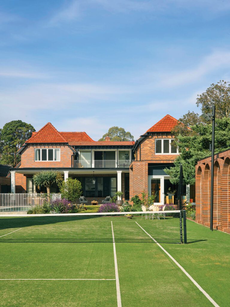 A view across the tennis court—built by former homeowner Daphne Akhurst, a grand slam winner—to the remodeled rear of the house; to the right is the newly constructed tennis house.