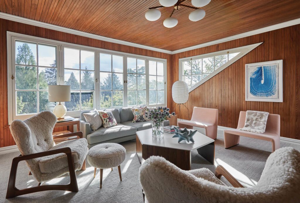 In the second-floor primary suite’s sitting room, windows are angled to follow the roofline; a print by Linda Colletta, Sky III, joins a Dufner Heighes–designed Stop coffee table, a D’Urso sofa, and vintage wing chairs reupholstered in shearling.