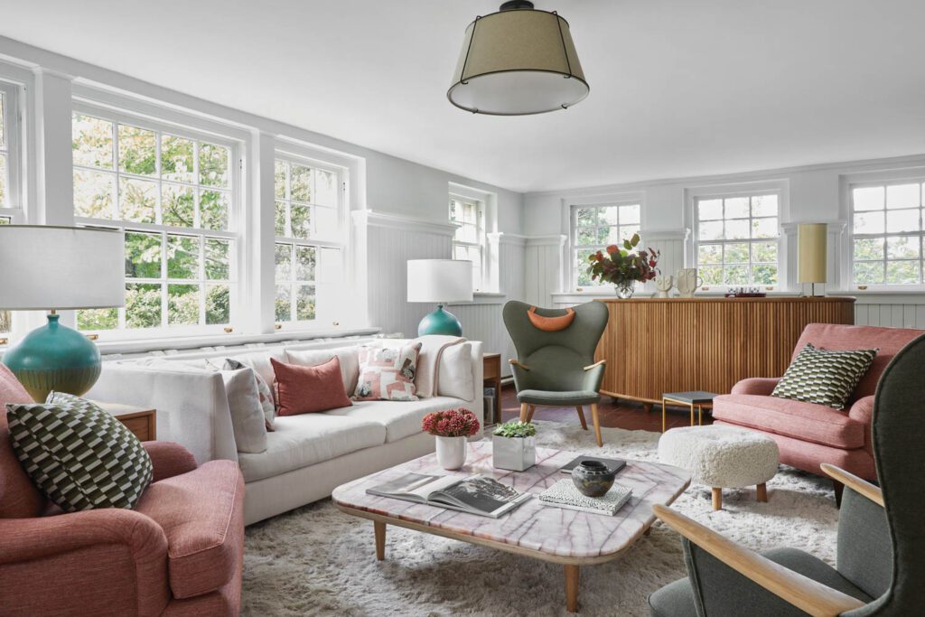 A custom bar in ribbed oak backdrops the lower-level family room, with a Hans Wegner Mama Bear chair and Simple side tables by Dufner Heighes; marble from Artistic Tile tops the Space Copenhagen Fly table.