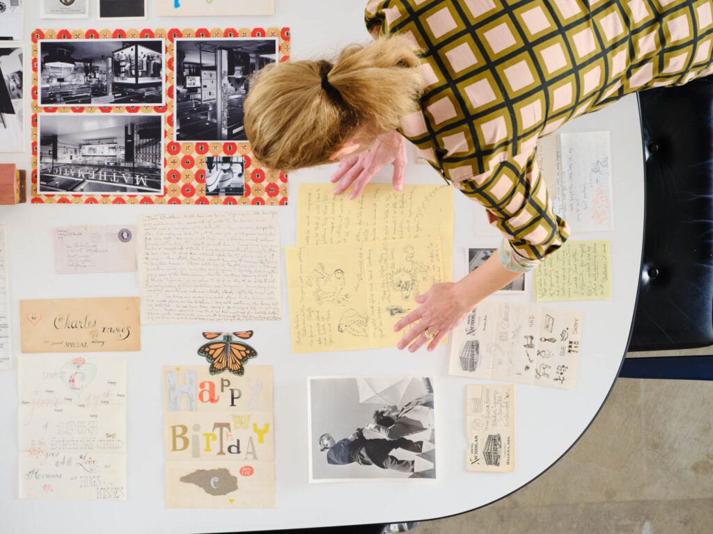 A woman organizing archival documents and images on a table.