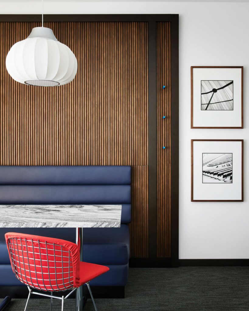 The guest room dining area, featuring American-walnut tambour wallcovering, a Harry Bertoia chair, Greta von Nessen pendant fixture, and images by Bauhaus photographer Ferenc Berko.