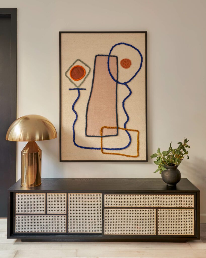 modern art atop a credenza with a gold lamp