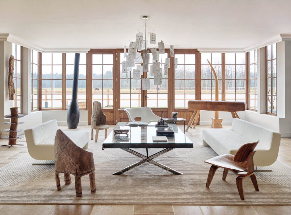 In the living room, a pair of vintage Shin and Tomoko Azumi sofas reupholstered in suede joins Charles and Ray Eames chairs, an Ingo Maurer chandelier, and wooden Senufo sculptures.