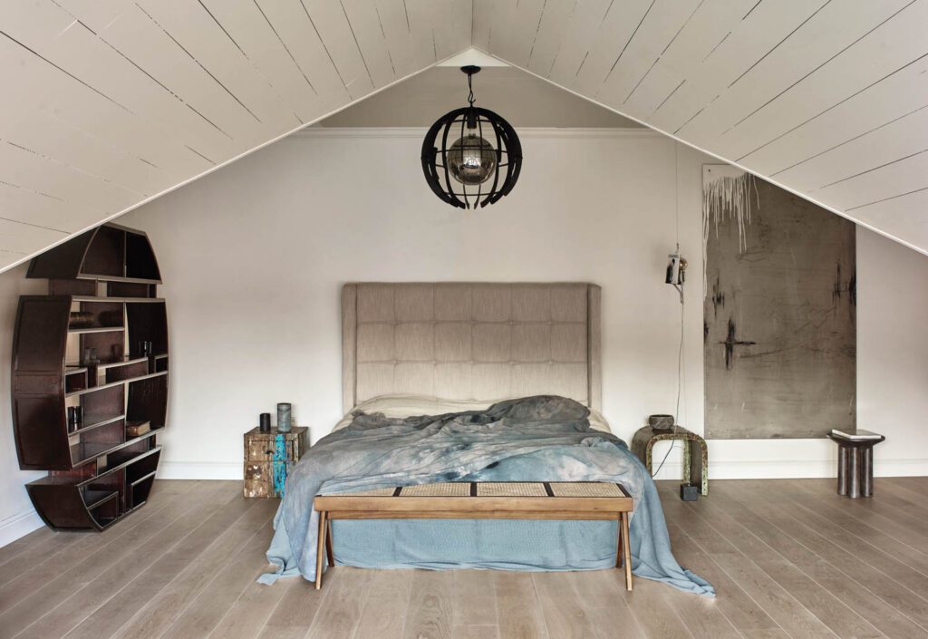 A vintage Pierre Jeanneret bench and an antique Asian display cabinet outfit the primary bedroom.