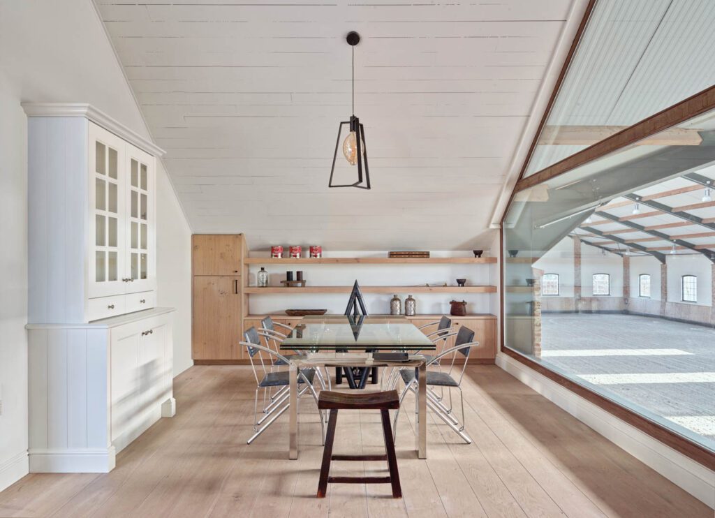 A new window wall in the dining room connects the residence with the arena; the 1980’s aluminum and leather chairs are Italian.