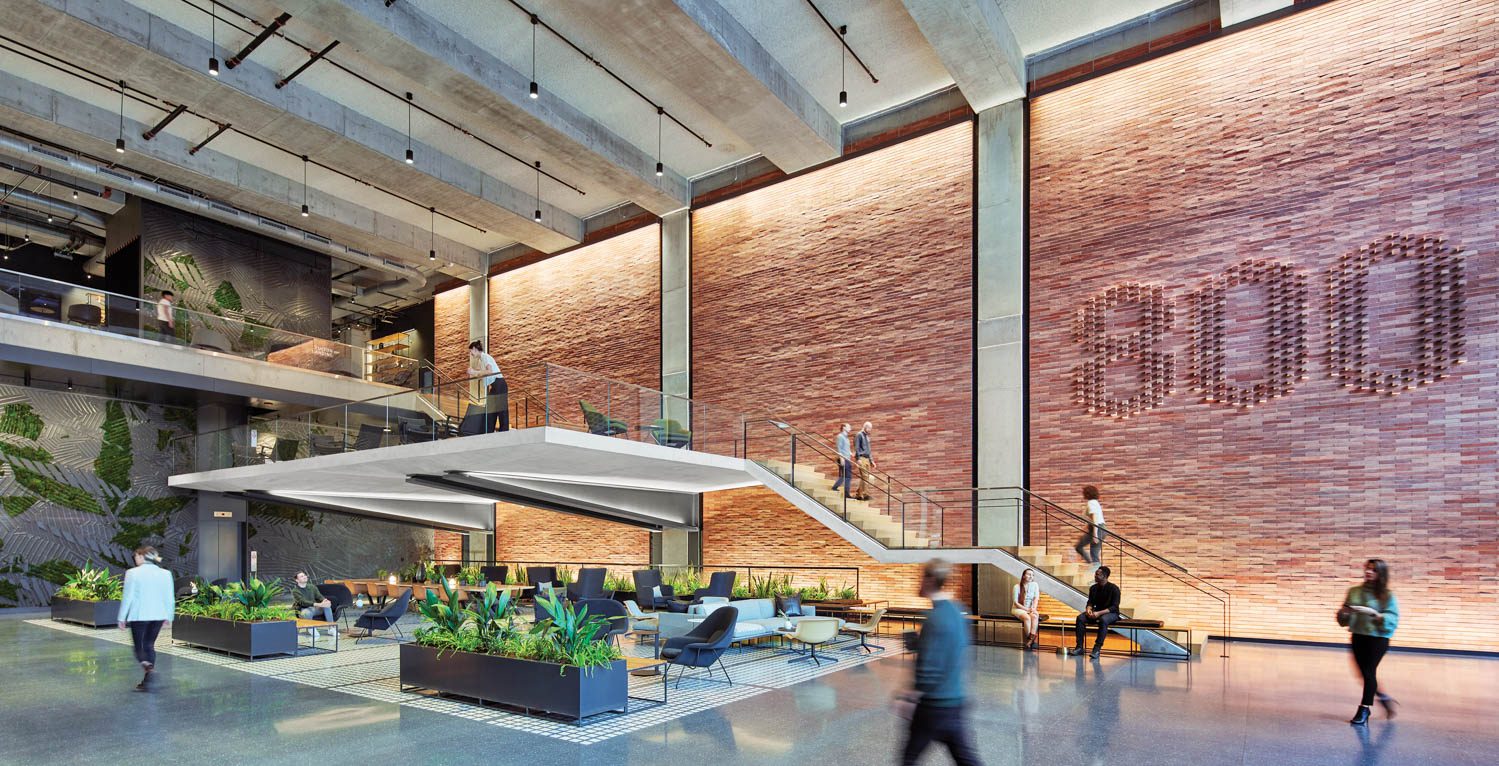 Canti­levered over the terrazzo-floored lobby, the concrete mezzanine level’s glass railing juxtaposes with exposed concrete and brick structural elements.