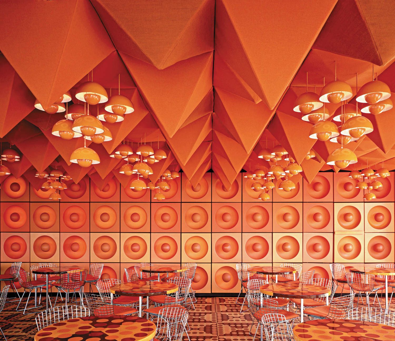 A vibrant orange interior with donutlike patterns on the walls and spikes descending from the ceiling. 