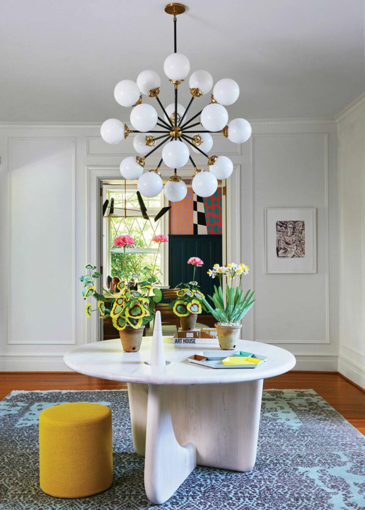 In the foyer, a portrait by Elizabeth Peyton is complemented by handmade paper flowers by Livia Cetti and a custom table by Casey Johnson.