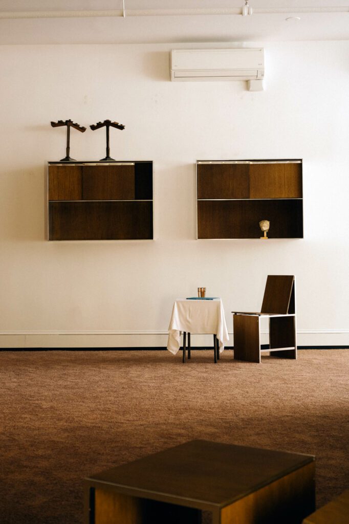 Shelves adorn the wall above a chair and small square table.