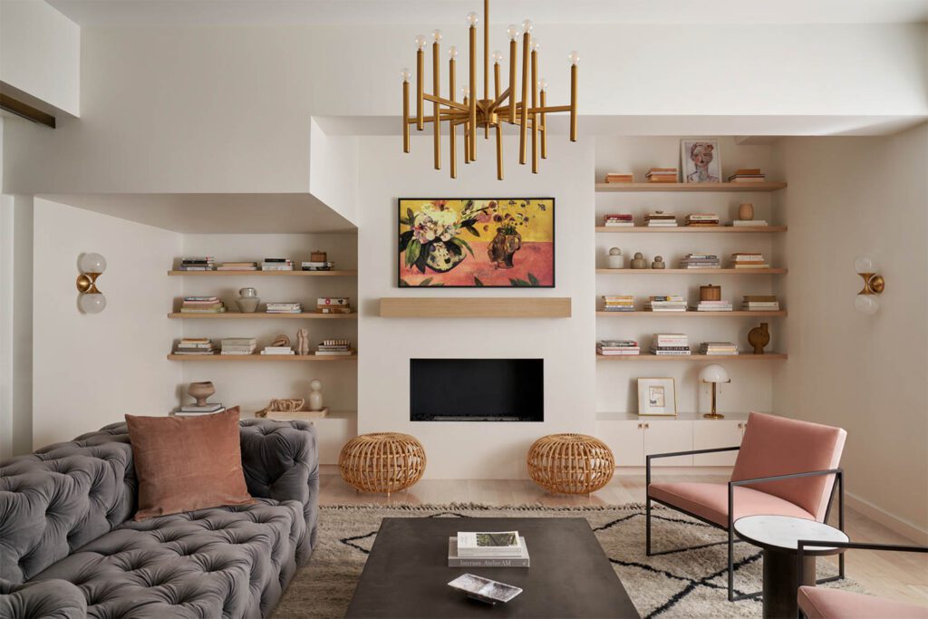 The living room is furnished with a sofa and a coffee table by RH, a Lulu & Georgia rug, Room & Board occasional chairs, a chandelier and wall sconces by Circa Lighting and a pair of rattan ottomans by Shoppe Amber Interiors. 