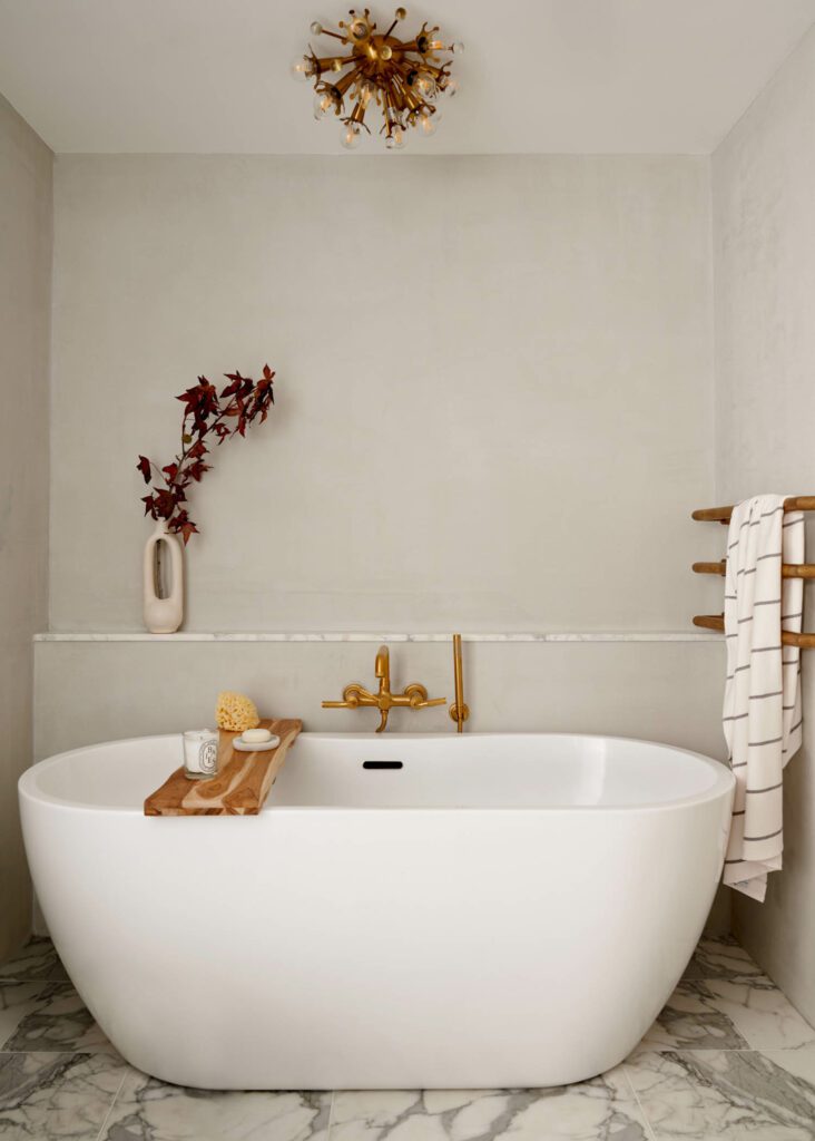 The primary bathroom is adorned with Calacatta Bettogli marble floor tiles and a Jonathan Adler pendant light.